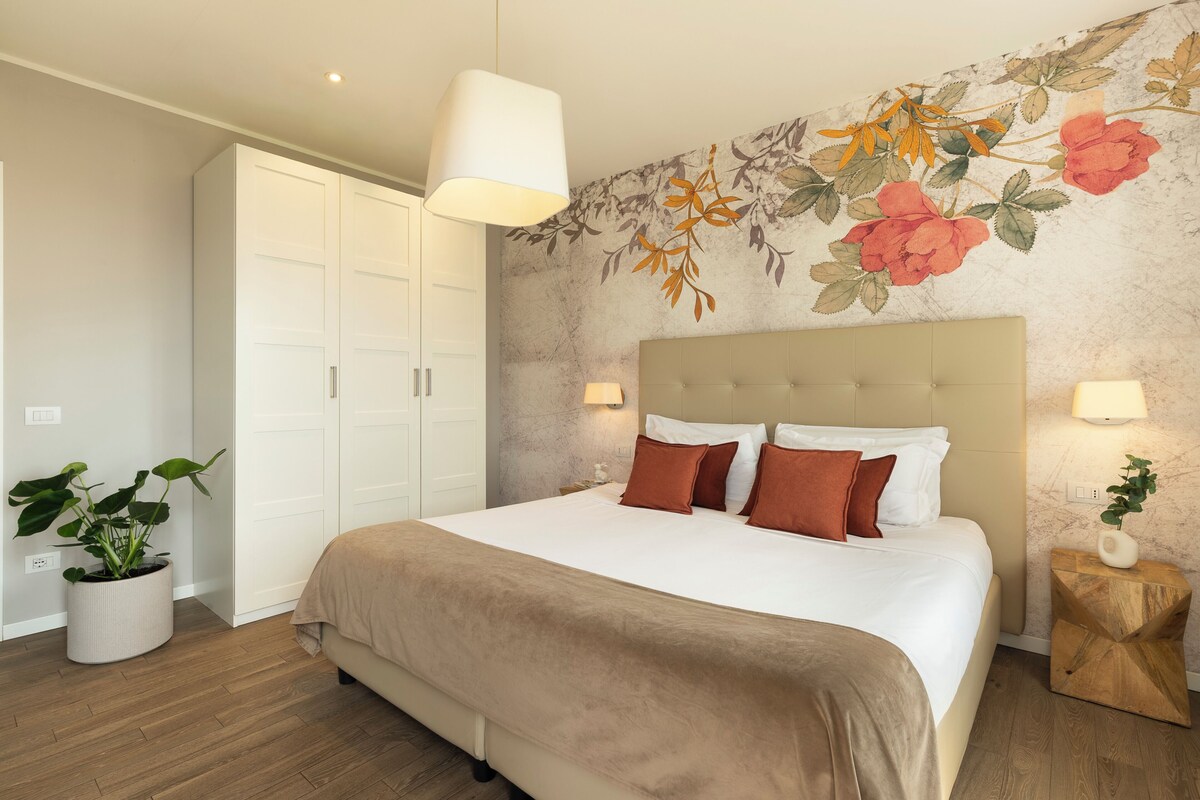 Ein Schlafzimmer mit Bett, Kleiderschrank, Wandbild und Topfpflanze.