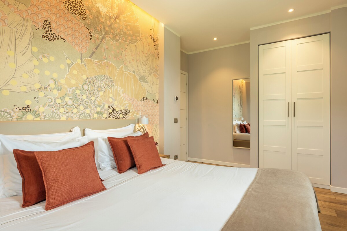Ein Schlafzimmer mit einem großen Bett, einem Kleiderschrank und einer Wand mit floralem Wandbild.