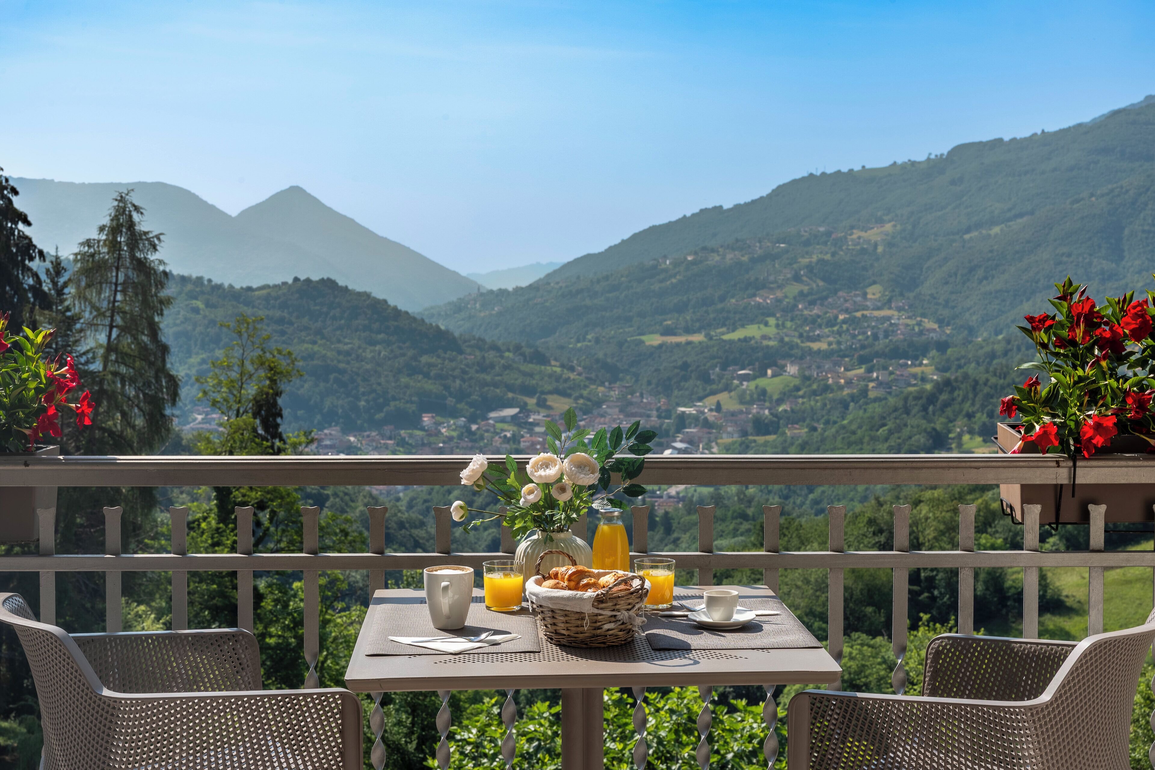 Un balcón con una mesa lista para el desayuno, con vistas a un paisaje montañoso.