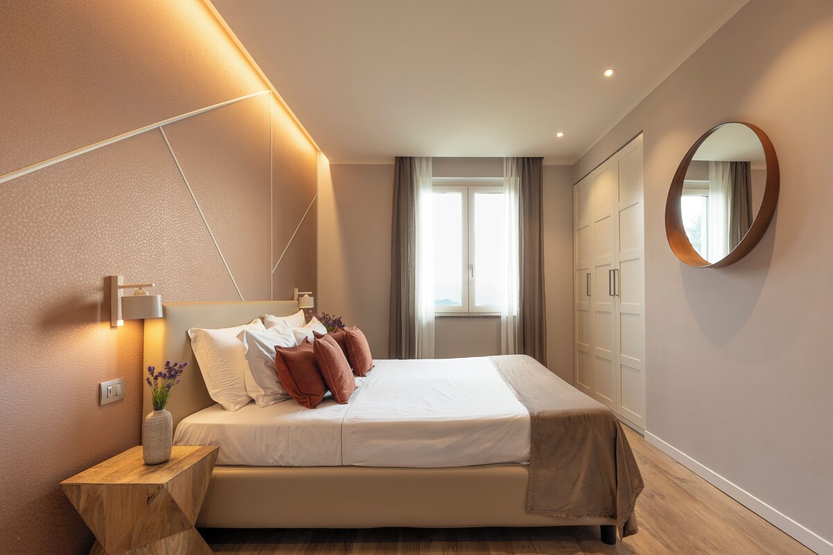 Ein Hotelzimmer mit Bett, Nachttisch, Lampe und einem großen Spiegel.