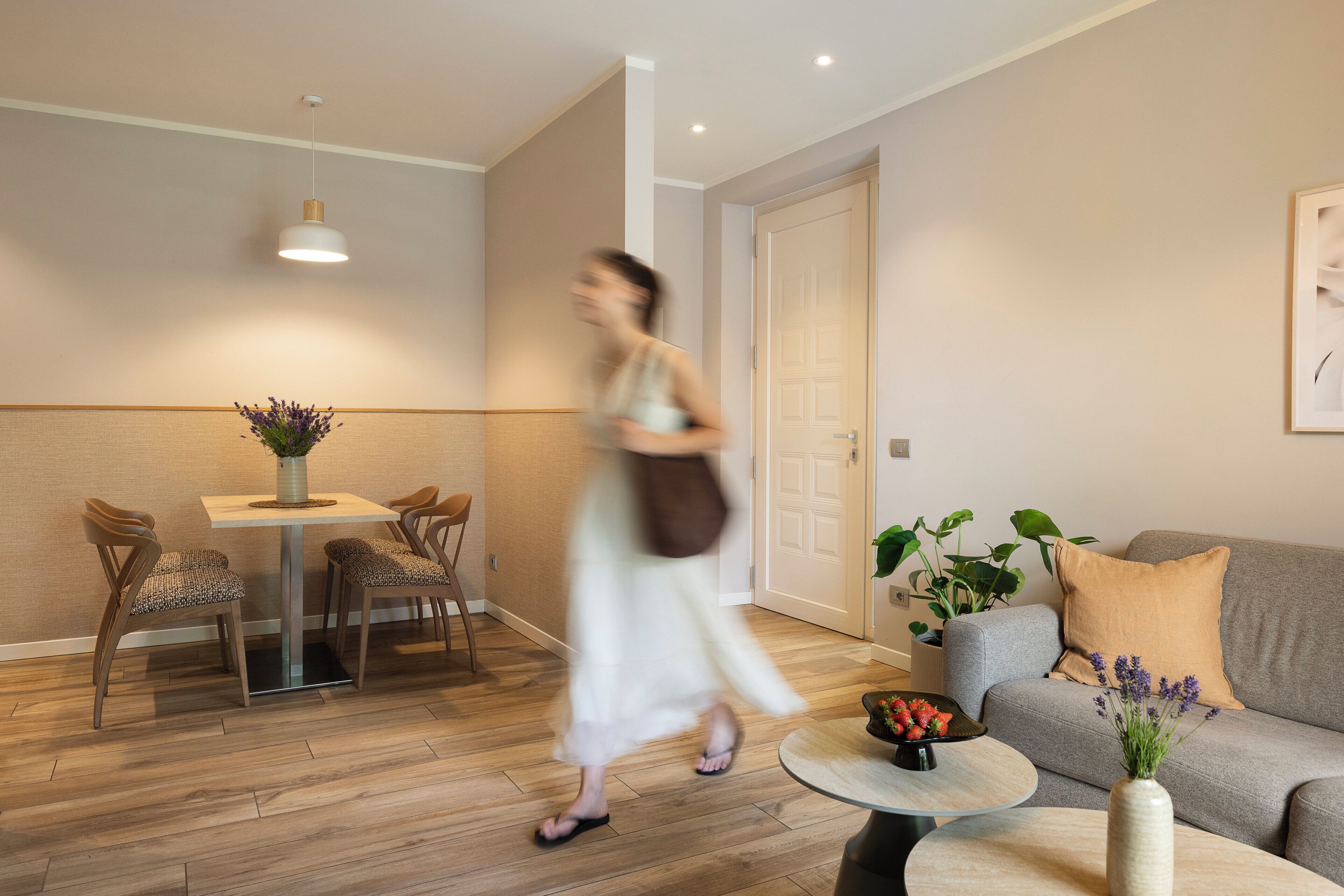 A modern living room with a dining area, a sofa, and a coffee table with a vase of flowers.