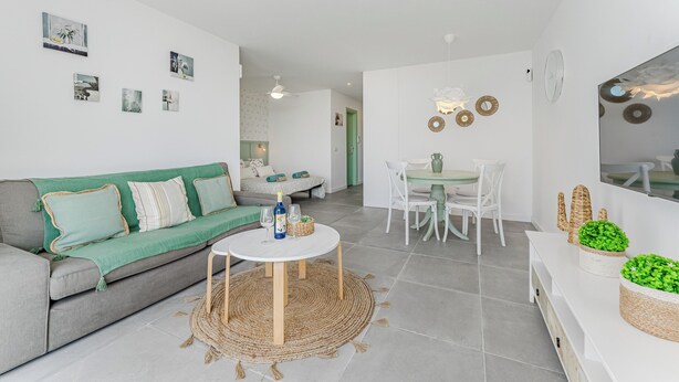 A modern living room with a grey sofa, a round coffee table, and a dining area with white chairs. - Home Holidays 423 (CN)