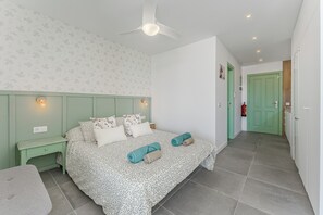 A bedroom with a bed, nightstands, a ceiling fan, and a green door. - Home Holidays 423 (CN)