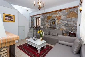 Ein Wohnzimmer mit Steinwand, einer Couch, einem Couchtisch mit Blumen, einer Treppe und einem Chandelier.