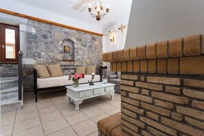 Ein Wohnzimmer mit Steinwand, Kamin, einer Couch, einem Couchtisch und einer Treppe.