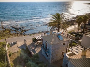 Ein Steinhaus mit Balkon, einer Palme und Blick aufs Meer.