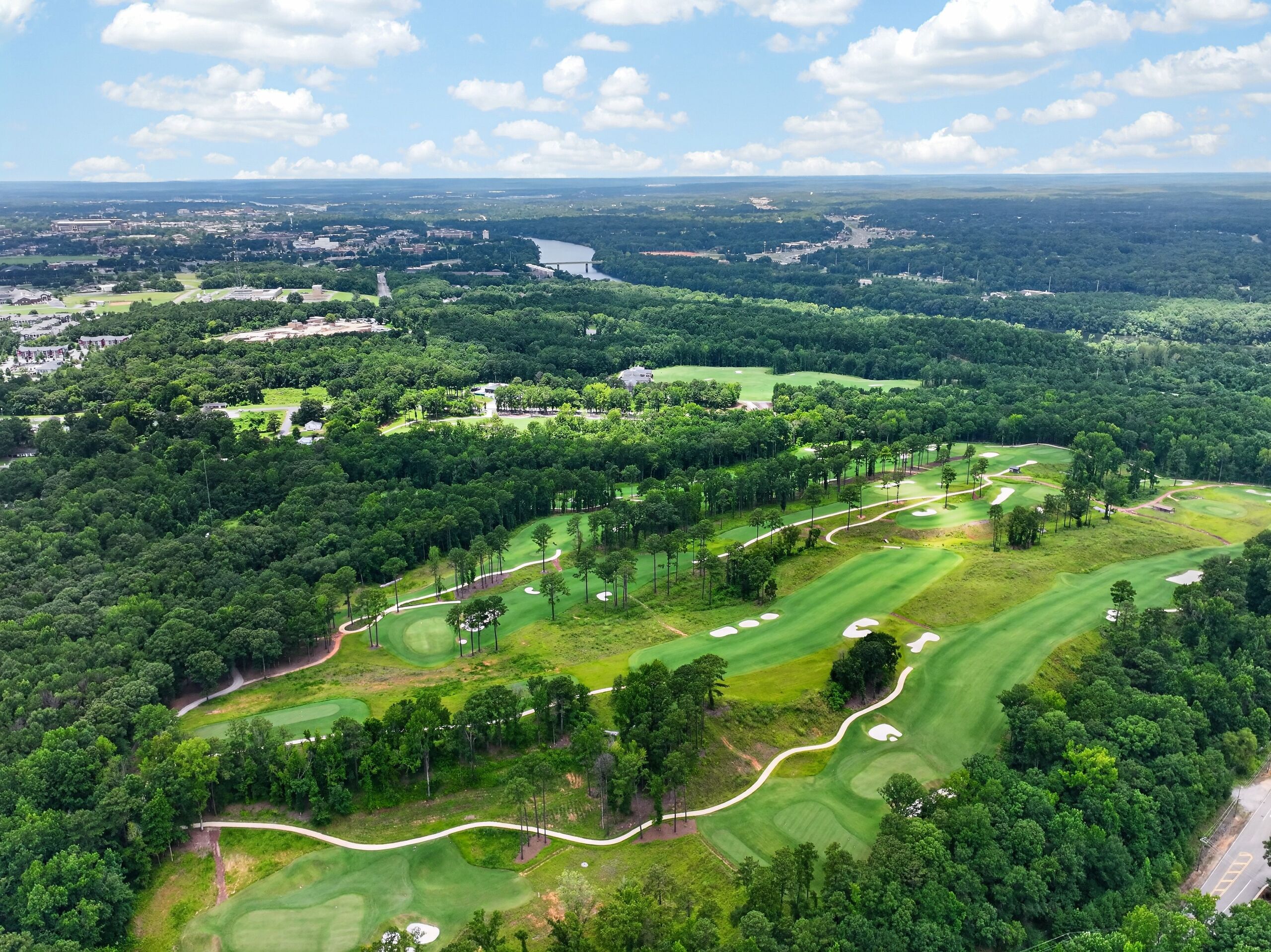 An aerial view of a golf course with multiple greens, fairways, and sand bunkers.
