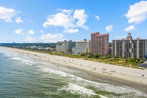 A beachfront hotel with multiple high-rise buildings, a sandy beach, and ocean waves. - Beach Colony Oceanfront 3BR Corner Retreat (Myrtle Beach)