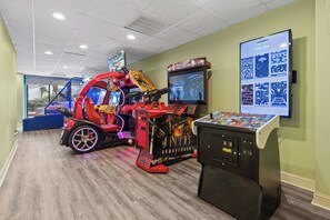 A gaming arcade with various arcade machines, including a racing game and a space-themed game. - Beach Colony Oceanfront 3BR Corner Retreat (Myrtle Beach)