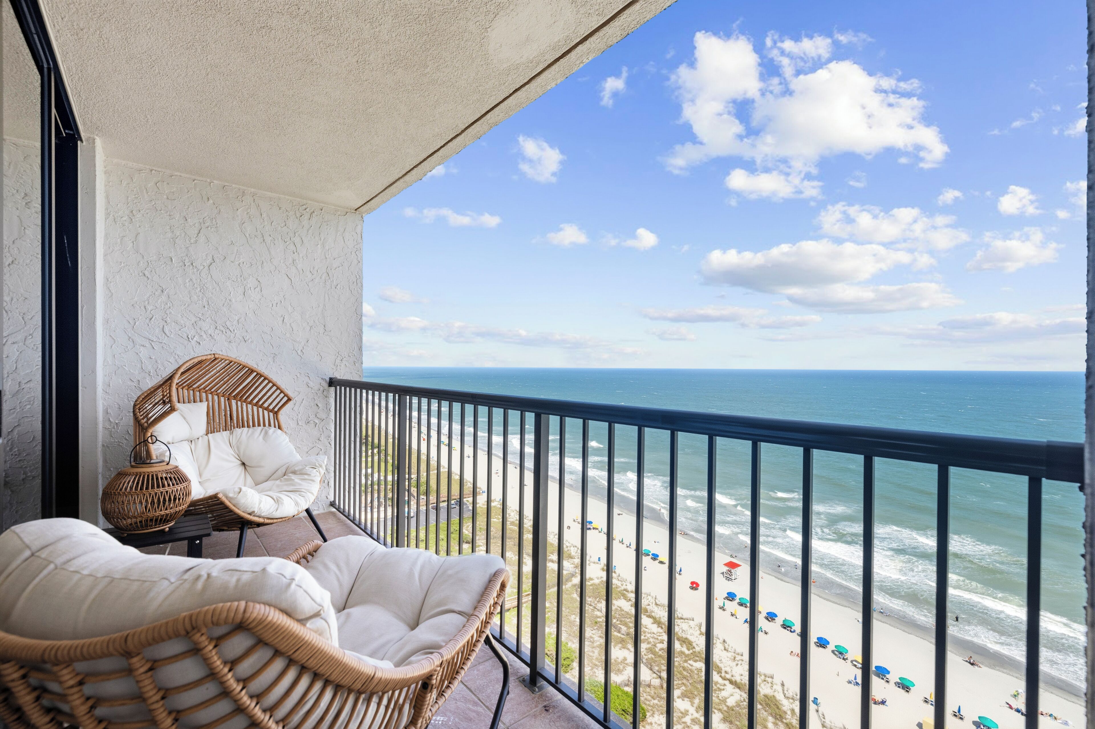 Een balkon met rieten stoelen en uitzicht op het strand.