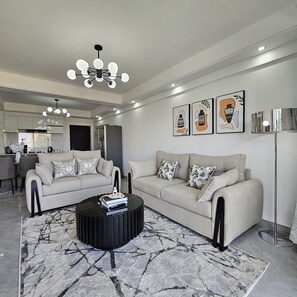 Ein modernes Wohnzimmer mit einer Sofagarnitur, einem Couchtisch und einer Chandelüster.