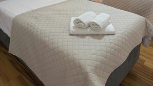 Quarto de hotel com duas camas, um quadro na parede e uma janela com cortinas.
