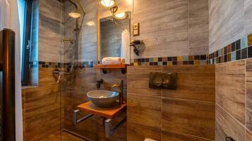Ein modernes Badezimmer mit einer gläsernen Duschkabine, einem Aufsatzwaschbecken und einem Holzwaschtisch.