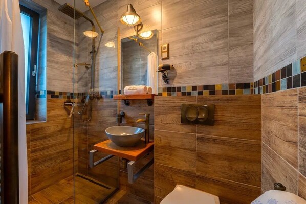 A modern bathroom with a glass-enclosed shower, a vessel sink, and a wooden vanity.