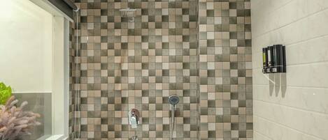 A bathroom with a checkered tile wall, a shower, and a marble floor.