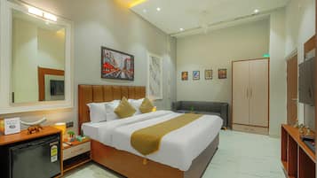 Habitación de hotel con cama, mesita de noche, armario, televisor y obras de arte en las paredes.