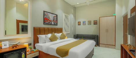 A hotel room with a bed, bedside table, wardrobe, TV, and artwork on the walls.