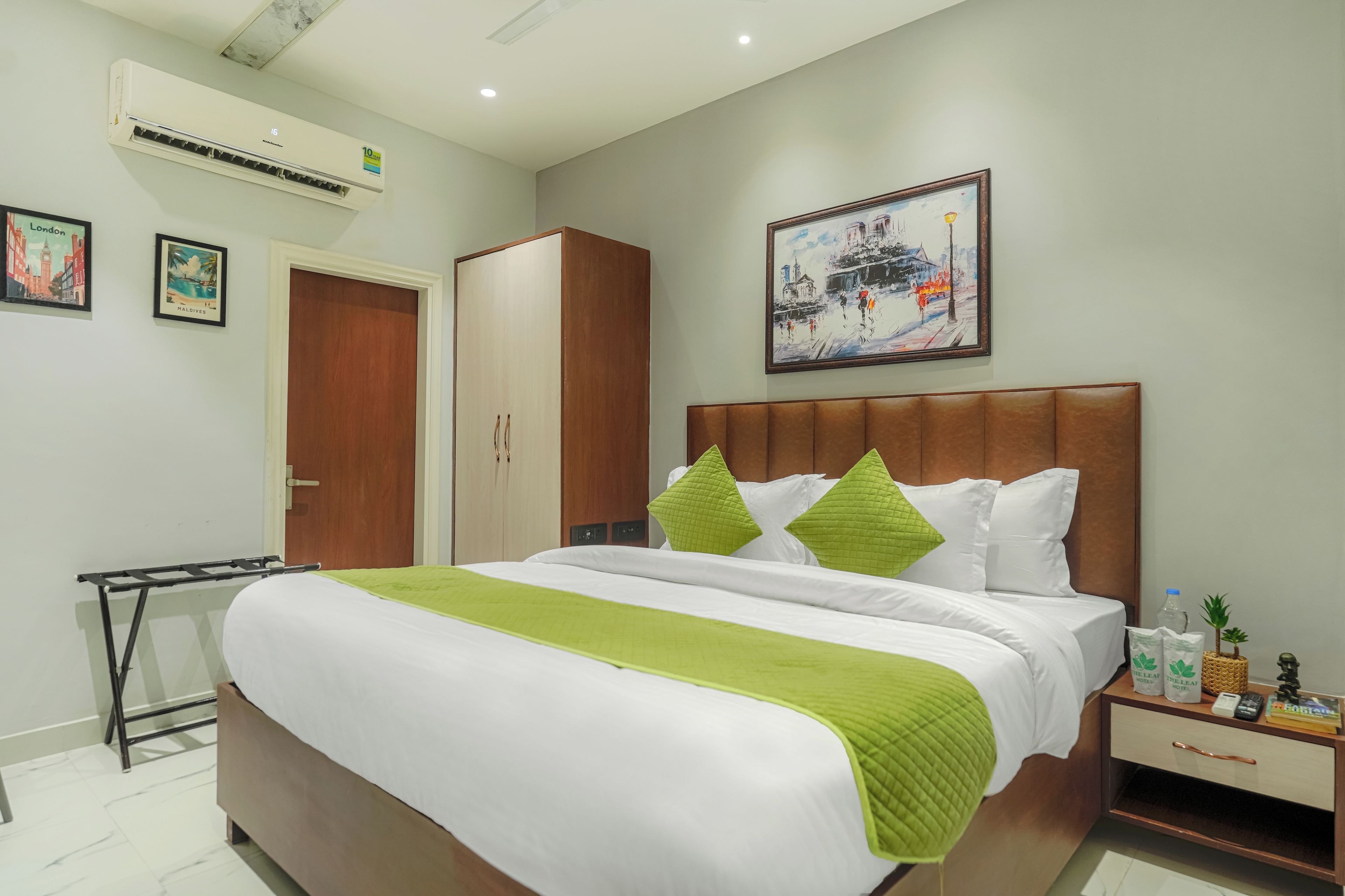 Quarto de hotel com cama, mesa de cabeceira, guarda-roupa e um quadro na parede.