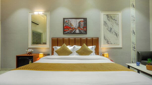 A hotel room with a bed, a nightstand, a lamp, a framed picture, and a marble wall.