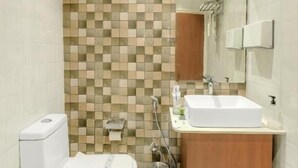 A bathroom with a tiled wall, a toilet, a sink, and a mirror.