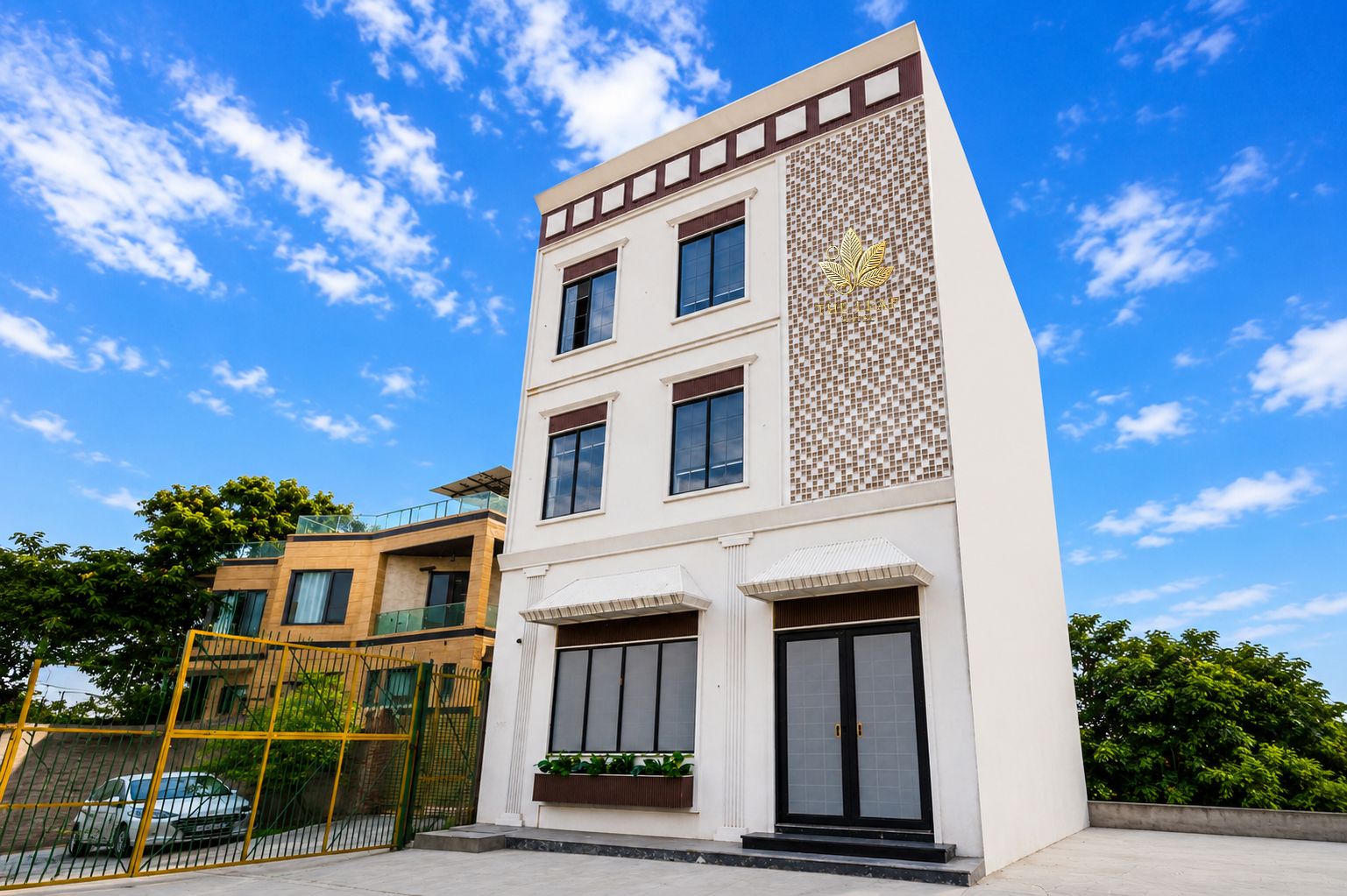 Un edificio moderno de dos pisos con techo plano, ventanas grandes y un diseño de azulejos decorativos en el lateral.