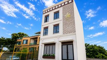 Un edificio moderno de dos pisos con techo plano, ventanas grandes y un diseño de azulejos decorativos en el lateral.