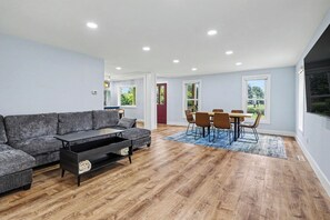 Ein modernes Wohnzimmer mit einer Eckcouch, einem Couchtisch und einem Essbereich mit Stühlen und einem Tisch.