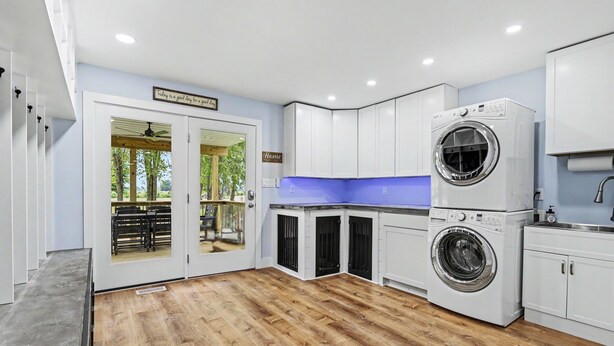 Une cuisine moderne avec des armoires blanches, un lave-linge intégré et une vue sur l’extérieur grâce à des portes vitrées.