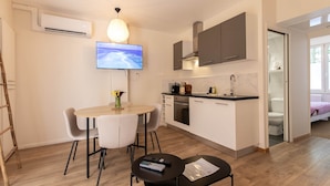A compact kitchen with a TV, a dining area with chairs, and a small table with a remote control. - Rez-de-chaussee de la Mairie - Clim - Terrasse (Arras)