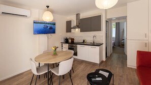 A modern kitchen with a flat-screen TV, a dining area with a wooden table and chairs, and a red chair. - Rez-de-chaussee de la Mairie - Clim - Terrasse (Arras)