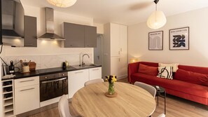 A modern kitchen with a dining area, a red sofa, and artwork on the wall. - Rez-de-chaussee de la Mairie - Clim - Terrasse (Arras)
