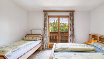 Una habitación con dos camas individuales, una ventana con cortinas, un radiador y un cabecero de madera.