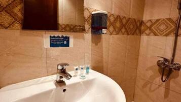 Un baño con lavamanos, espejo, ducha y toallero.