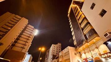 Une vue nocturne d’une ville, avec ses bâtiments modernes, ses lampadaires et une rue animée.