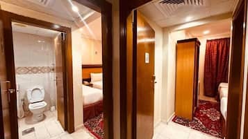 A hotel room with a bathroom, a bed, and a red carpet.