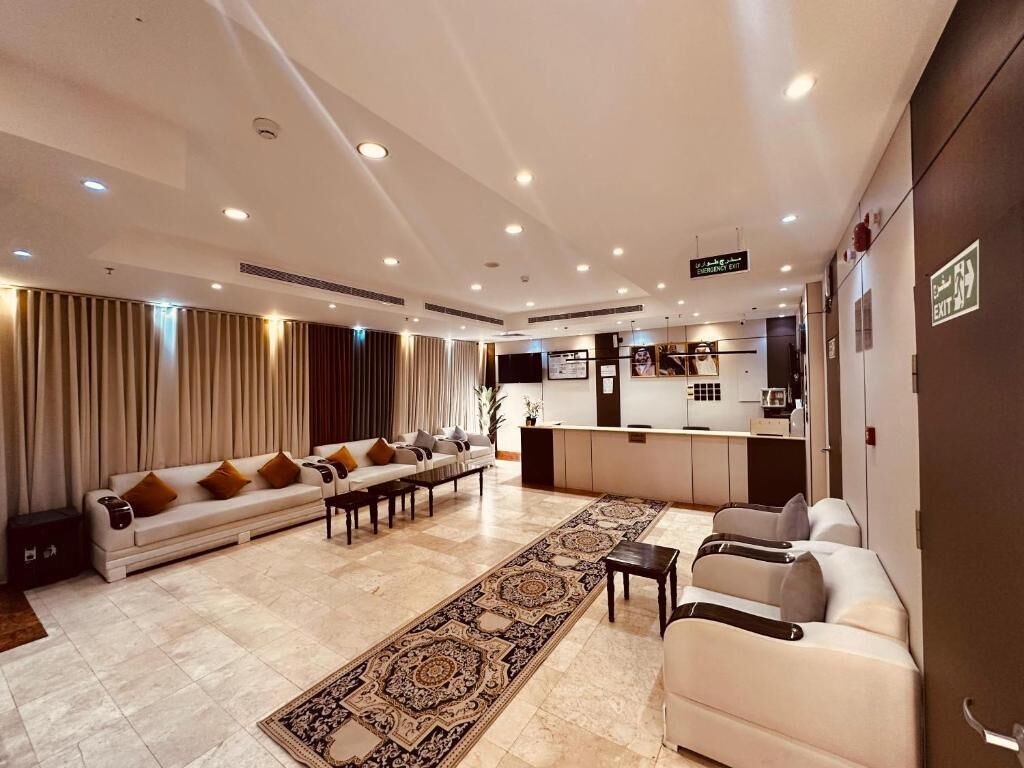 Un hall d’hôtel comprenant un comptoir d’accueil, un espace salon et un tapis à motifs.