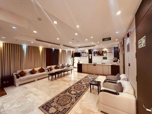 Un vestíbulo de hotel con mostrador de recepción, zona de estar y alfombra estampada.
