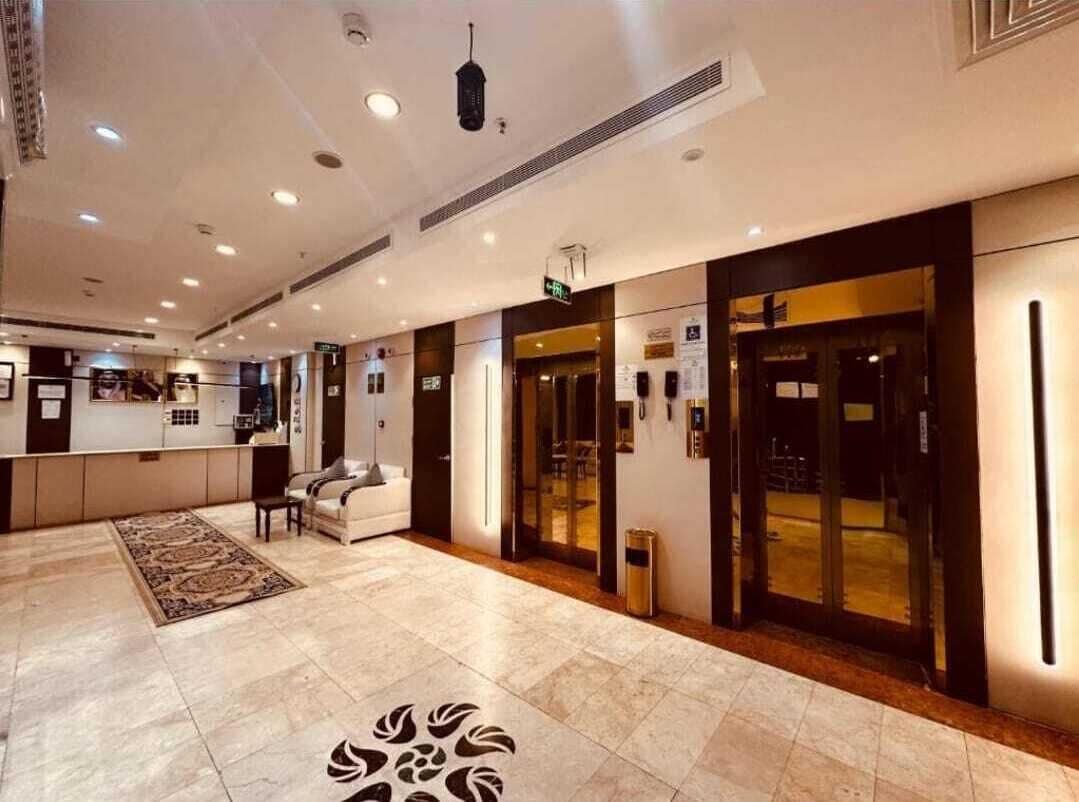 A hotel lobby with a reception desk, seating area, and a patterned floor design.