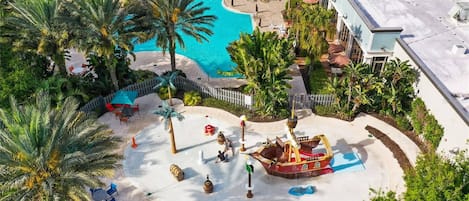 Un complexe hôtelier doté d’une grande piscine, de palmiers et d’un espace de jeux aménagé en forme de bateau.