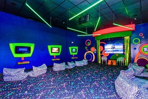 A room with multiple screens, colorful geometric wall decorations, and patterned seating. - Upstay Family Getaway With Pool Near Disney (Davenport)