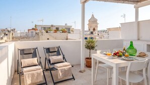 En tagterrasse med to liggestole, et spisebord med morgenmad og udsigt til en bygning med kuppel i det fjerne.
