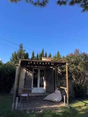 A small, rustic outdoor structure with a wooden pergola, a single door, and a chair. - Studio in the Heart of Provence (Châteaurenard)
