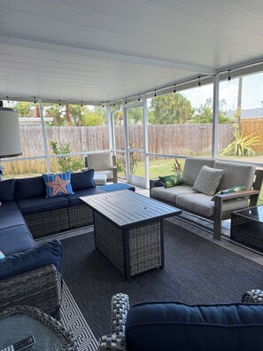 A covered patio with a sectional sofa, a coffee table, and a chair. - Serenity in Seminole/Madeira Beach (Seminole)