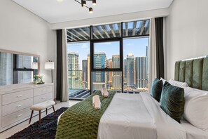 Un dormitorio moderno con un ventanal grande, una cama, un tocador y un espejo.