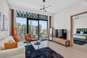 Ein modernes Wohnzimmer mit großem Fernseher, einer Couch, einem Couchtisch und Blick auf die Stadt.