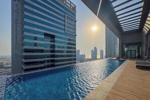 Una piscina con vista al horizonte de la ciudad, edificios modernos y un cielo despejado.