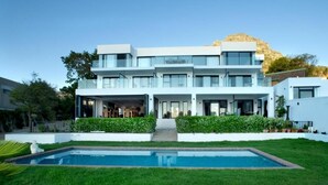A modern multi-story house with a swimming pool in the front yard.