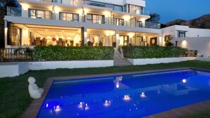 A modern multi-story house with a swimming pool in the foreground.