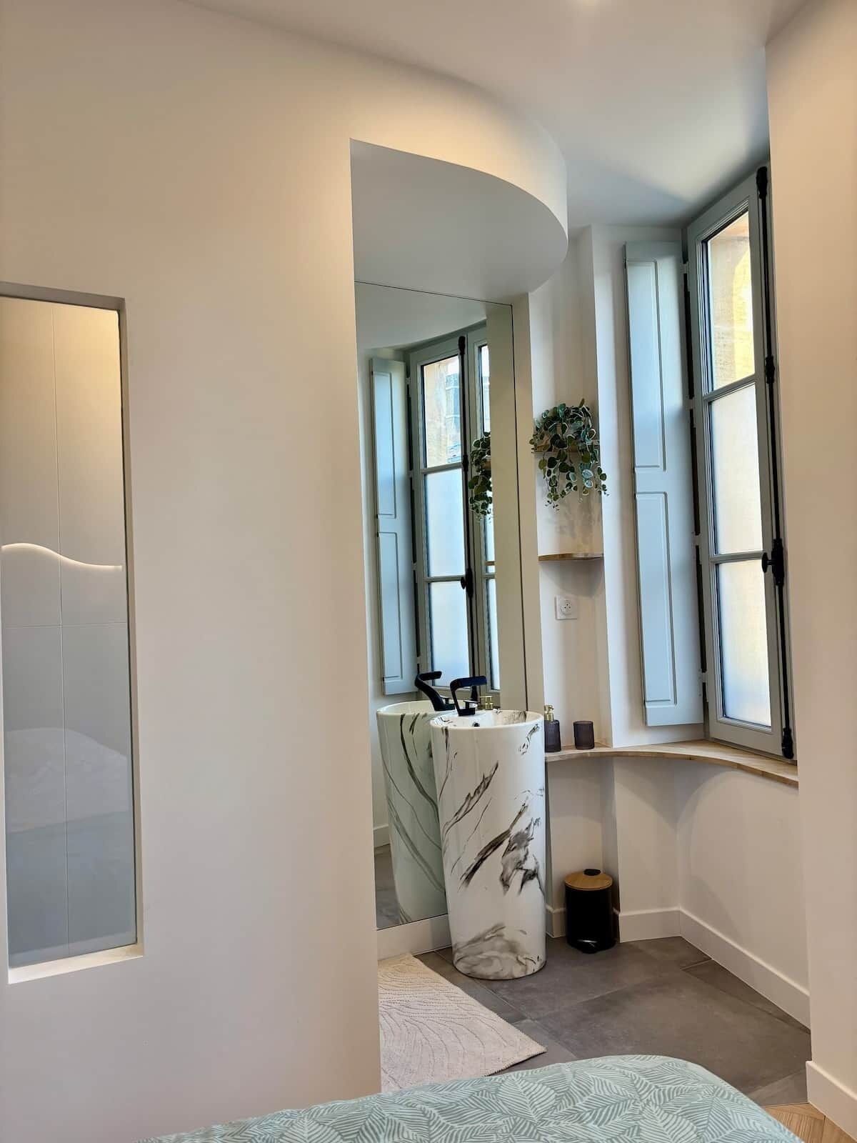 Een moderne badkamer met een gebogen douche, een marmeren wastafel en een raam met uitzicht.