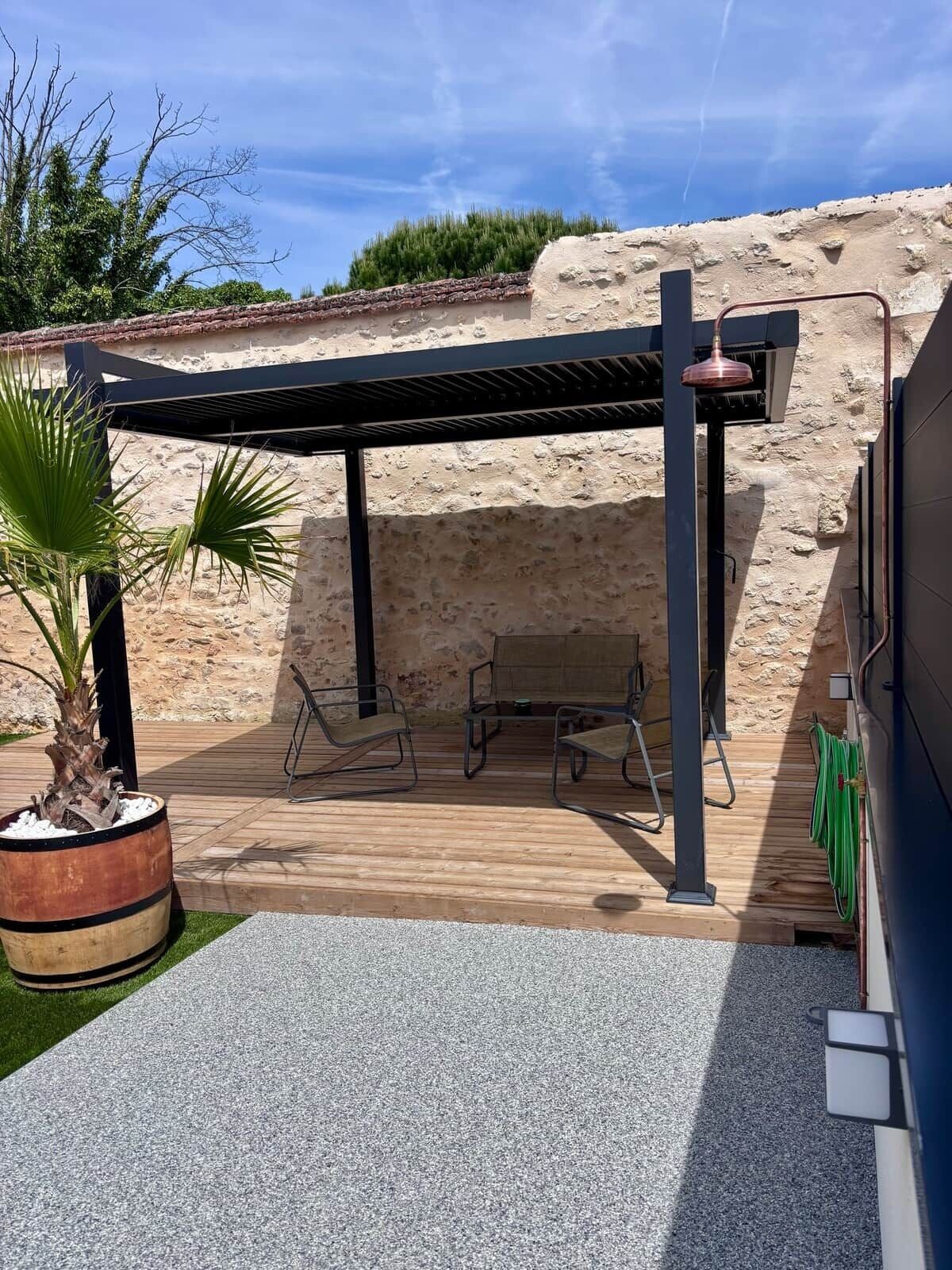 En uteplats med en pergola, sittplatser och en krukväxt.